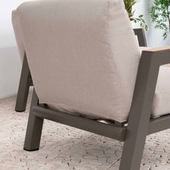 Stylish beige outdoor lounge chair with a sturdy gray metal frame, perfect for garden or patio relaxation, surrounded by lush green plants for a modern outdoor living space.