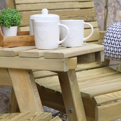 Rustic wooden outdoor patio table with white ceramic mugs, teapot, and potted plant, perfect for garden relaxation and outdoor entertaining.