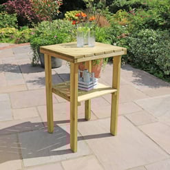 - Wooden outdoor patio side table with glass pitcher and tumbler set on a garden stone patio.