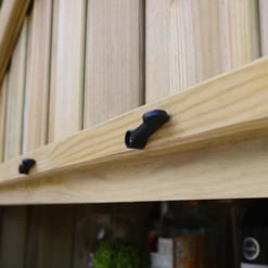 Natural wood birdhouse with black feeding ports, mounted on wooden support, featuring vertical wooden panels for outdoor wildlife feeding and garden decor.