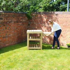 Designed landscape furniture outdoor garden patio wooden table with greenery.
