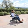 Relaxing woman enjoying outdoor patio with Adirondack chair, surrounded by flowering bushes and scenic countryside at Empire Home and Garden.