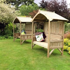 Cozy outdoor wooden garden benches with canopies surrounded by lush greenery and vibrant flowers in a landscaped backyard, perfect for relaxation and outdoor leisure.