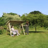 Relaxing garden swing with women enjoying outdoor leisure in a lush green backyard.