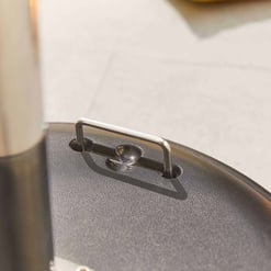 Stainless steel hinge on a grill lid, close-up shot showing durable outdoor cooking equipment.