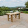 Rustic wooden outdoor dining table on stone patio with garden and lush landscape background, perfect for backyard entertaining and outdoor living.