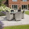 Elegant outdoor patio dining set with woven rattan chairs and glass-top table, perfect for garden entertaining and outdoor living. Beautifully landscaped backyard with flowering plants and lush lawn.
