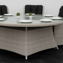 Elegant outdoor dining table with a glass top and woven wicker base, surrounded by comfortable cushioned chairs, perfect for patio or garden gatherings.