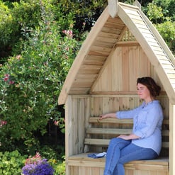 Handmade wooden garden nook with roof, perfect for relaxing outdoors in a lush garden setting, ideal for outdoor living and backyard furniture.