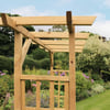 Wooden pergola under construction in a lush garden with flowering plants and trees, perfect for outdoor home and garden enhancement, gardening projects, and backyard landscaping.