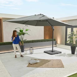 Light gray outdoor patio umbrella with adjustable height, providing shade for a modern backyard space with potted plants and stylish decor.