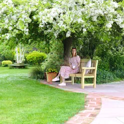 Lush garden with blooming trees and vibrant greenery, featuring a cozy wooden bench for relaxation in a peaceful outdoor space. Perfect for garden enthusiasts and outdoor living.