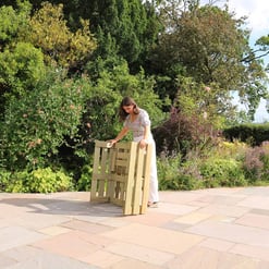 Stacking wooden garden furniture outdoors in a lush, landscaped backyard.