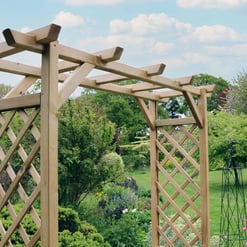Wooden garden arbor with lattice sides in lush outdoor garden setting.