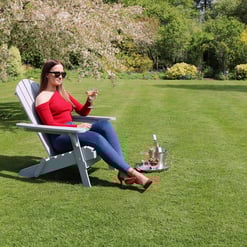 Relaxing woman enjoying garden lawn with wine, outdoor patio furniture, and lush greenery for garden and outdoor living inspiration.
