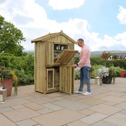 Rotating beverage bar made of natural wood on outdoor patio, landscaped garden, and scenic countryside view.