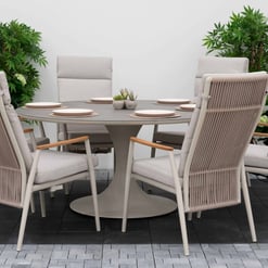 Modern outdoor dining set with six cushioned chairs and a round table, surrounded by lush green plants, perfect for stylish garden or patio entertaining.