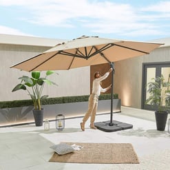Solid beige outdoor patio umbrella with adjustable crank, ideal for garden or backyard shade solutions, incorporated into modern home decor with potted plants and decorative lighting.