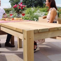 Natural outdoor wooden dining table with benches set in a garden, perfect for outdoor entertaining and garden furniture ideas, showcasing high-quality craftsmanship and durability.