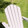 Adirondack chair on a lush green lawn with tree shadows, perfect for outdoor garden relaxation and patio decor.