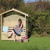 Garden wooden garden shed with cozy seating area and woman reading, gardening tools, flowers, outdoor furniture, backyard patio, landscaped garden, floral accessories, leisure outdoor space, Empire Home and Garden.