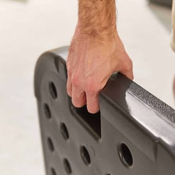Heavy-duty black rubber fitness weight plate with a textured grip surface, used for gym workouts and strength training. The plate features multiple holes for easy handling and secure fitting on barbells.