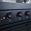 Gas grill control knobs with temperature settings and ignition on a black outdoor cooking appliance.