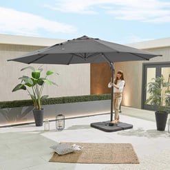 Stylish outdoor patio with large grey umbrella, potted plants, and cozy decor, perfect for garden entertaining and shade. Modern backyard setup ideal for relaxing and outdoor gatherings.