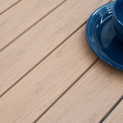 Bright blue ceramic plates and bowls set on a natural wood outdoor patio table, showcasing stylish outdoor dinnerware for backyard entertaining and garden-inspired home decor.