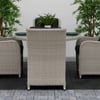 Elegant outdoor patio table and wicker chairs with black cushions, surrounded by lush green plants, perfect for home garden decor and outdoor dining setups.