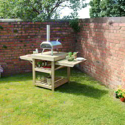 Outdoor barbecue station with brick wall backdrop and lush green grass, perfect for backyard entertaining and garden events.