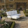 Modern outdoor patio sofa with white cushions in a beautifully landscaped garden, perfect for outdoor living and relaxation, featuring garden flowers and elegant design.