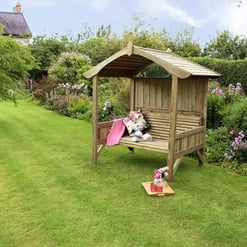 Cozy wooden garden bench with canopy surrounded by lush greenery and colorful flowers, perfect for relaxing outdoor spaces.