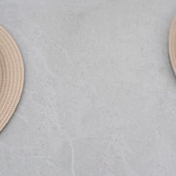 Soft beige woven placemats with white ceramic plates on a light gray textured surface, ideal for stylish home and garden dining setups. Perfect for enhancing outdoor or indoor gatherings with elegant tableware.