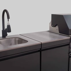 Modern commercial kitchen sink with black faucet and stainless steel countertop, ideal for food prep and cleaning in restaurant or catering environments.