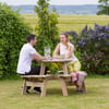 Relaxing outdoor dining with a couple at a wooden picnic table surrounded by lush greenery and vibrant purple flowering bushes, perfect for garden entertainment or backyard meals.