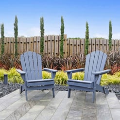Adorable blue Adirondack chairs in a stylish backyard garden setting featuring lush plants and a wooden fence, perfect for relaxing outdoors.