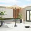 Bright outdoor patio with large beige umbrella, potted tropical plants, modern decor, and comfortable seating for backyard relaxation and entertaining.