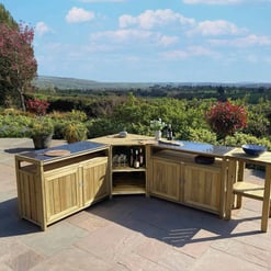 Elegant outdoor garden kitchen with natural wood cabinets and a granite countertop, set against lush scenic landscape and blooming trees, perfect for outdoor entertaining and dining.