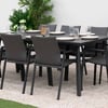 Sleek black outdoor dining table with modern gray upholstered chairs set up for a gathering, surrounded by lush green plants and white hydrangeas, perfect for stylish garden entertaining.