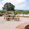 Bright outdoor patio with wooden dining table, surrounded by potted flowers and lush garden, perfect for entertaining and enjoying scenic countryside views.