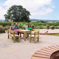 Bright outdoor patio with wooden dining table, surrounded by potted flowers and lush garden, perfect for entertaining and enjoying scenic countryside views.