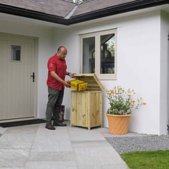 Weatherproof outdoor storage box for garden tools and supplies at a modern home entrance.