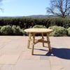 Wooden outdoor table on patio with garden and scenic landscape background.
