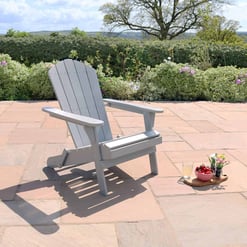 Adirondack-style outdoor chair on a spacious patio with scenic garden view and blooming shrubs.