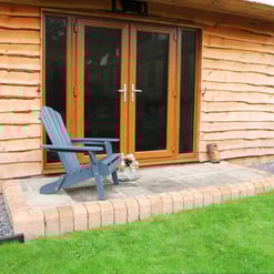Adirondack chair on a cozy backyard patio with wooden exterior walls, surrounded by potted plants and a manicured lawn, showcasing outdoor garden furniture and home garden design.