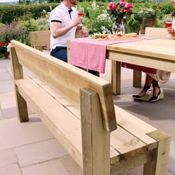 Elegant outdoor wooden dining table with matching benches in a lush garden setting, perfect for al fresco meals and gatherings.