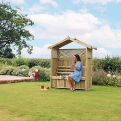 Cozy wooden garden shelter with bench, ideal for outdoor relaxation and patio decor, surrounded by lush greenery and vibrant flowers in a spacious yard.