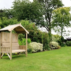 Rustic wooden garden bench with a canopy, surrounded by lush greenery, flowering plants, and mature trees in a well-maintained backyard, ideal for outdoor relaxation.