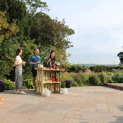 Elegant outdoor garden party with a portable bar, lush greenery, and scenic views, showcasing home and garden entertaining spaces at Empire Home and Garden.